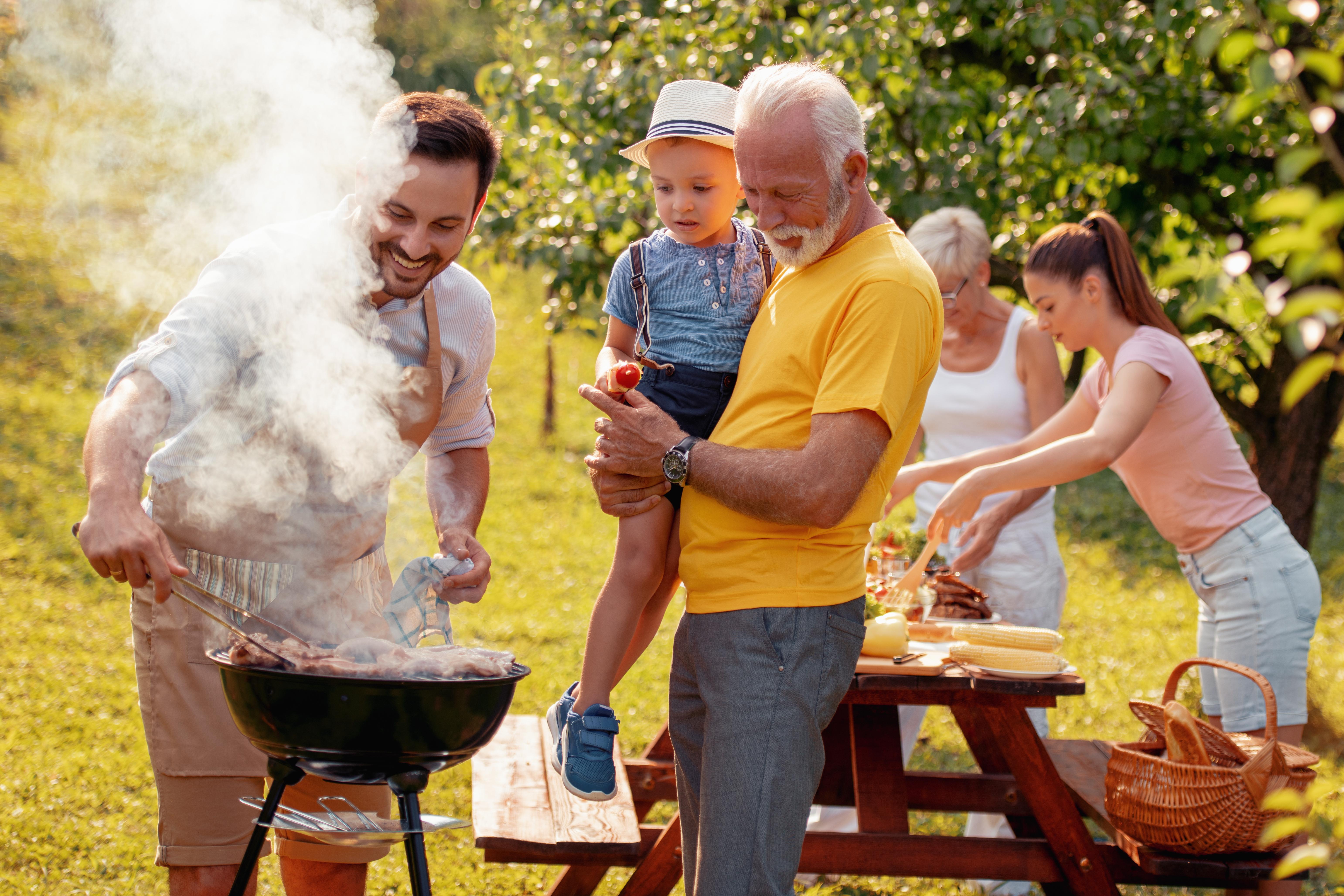 Multi-generational family enjoys a backyard barbecue picnic together on a sunny day. Multi-generational family enjoys a backyard barbecue picnic together on a sunny day.