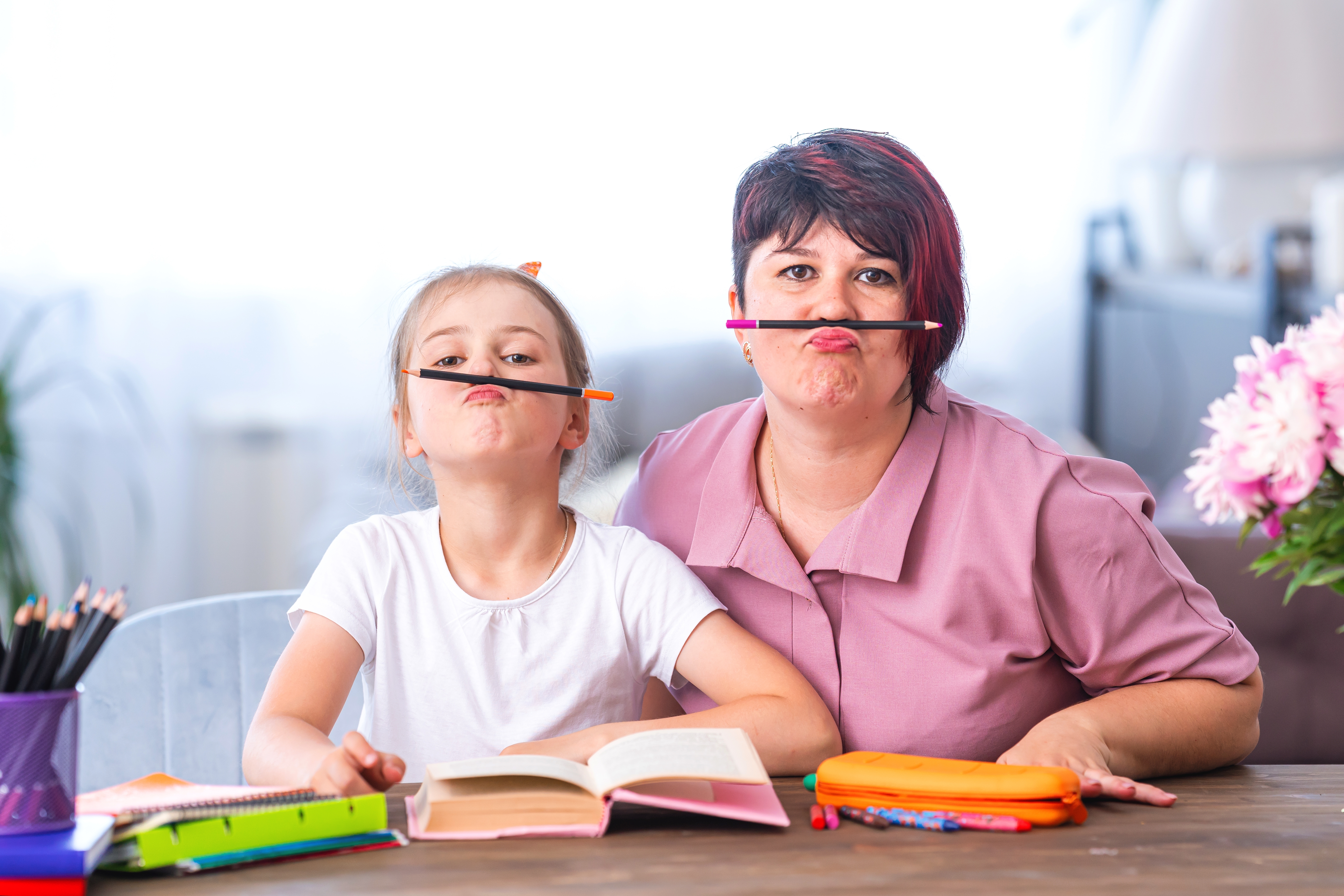 Mom and daughter being silly while studying at a table Mom and daughter being silly while studying at a table