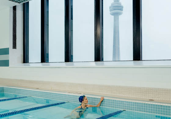 Woman swimming in the pool at the Toronto Athletic Club, with CN Tower in the background