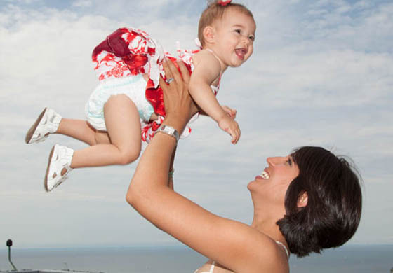 Young fit woman smiling and throwing her baby girl up into the air