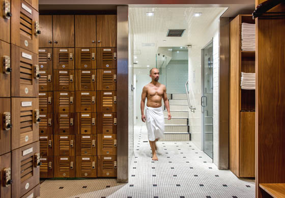 Fit middle aged man wrapped in a towel, walking through the men's locker room at the Toronto Athletic Club