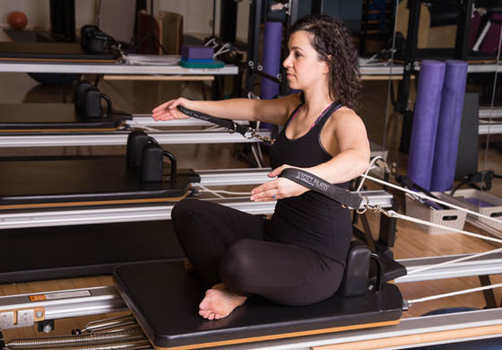 Young, fit woman - our Pilates Director, Stephanie Schrieber - doing a Pilates workout on the reformer in the Pilates loft at the Toronto Athletic Club