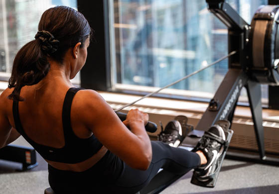 Fit woman on the rowing machine in the Strength Gym at the Toronto Athletic Club, overlooking the lake and city below