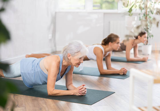 3 women (2 younger and 1 older) completing a mat Pilates workout in a studio